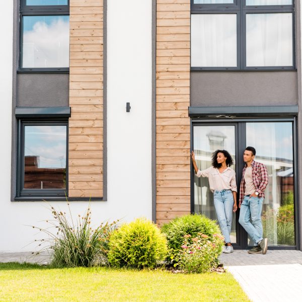 full length view of african american wife and husband leaning on door while standing outdoors and