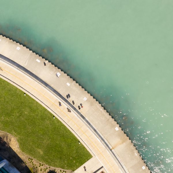 The sidewalk looks like a gear as people walk along next to turquoise tinted water