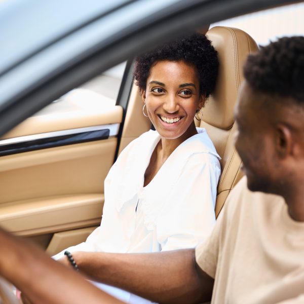 African American man holding girlfriends hand, couple sitting in a comfortable car