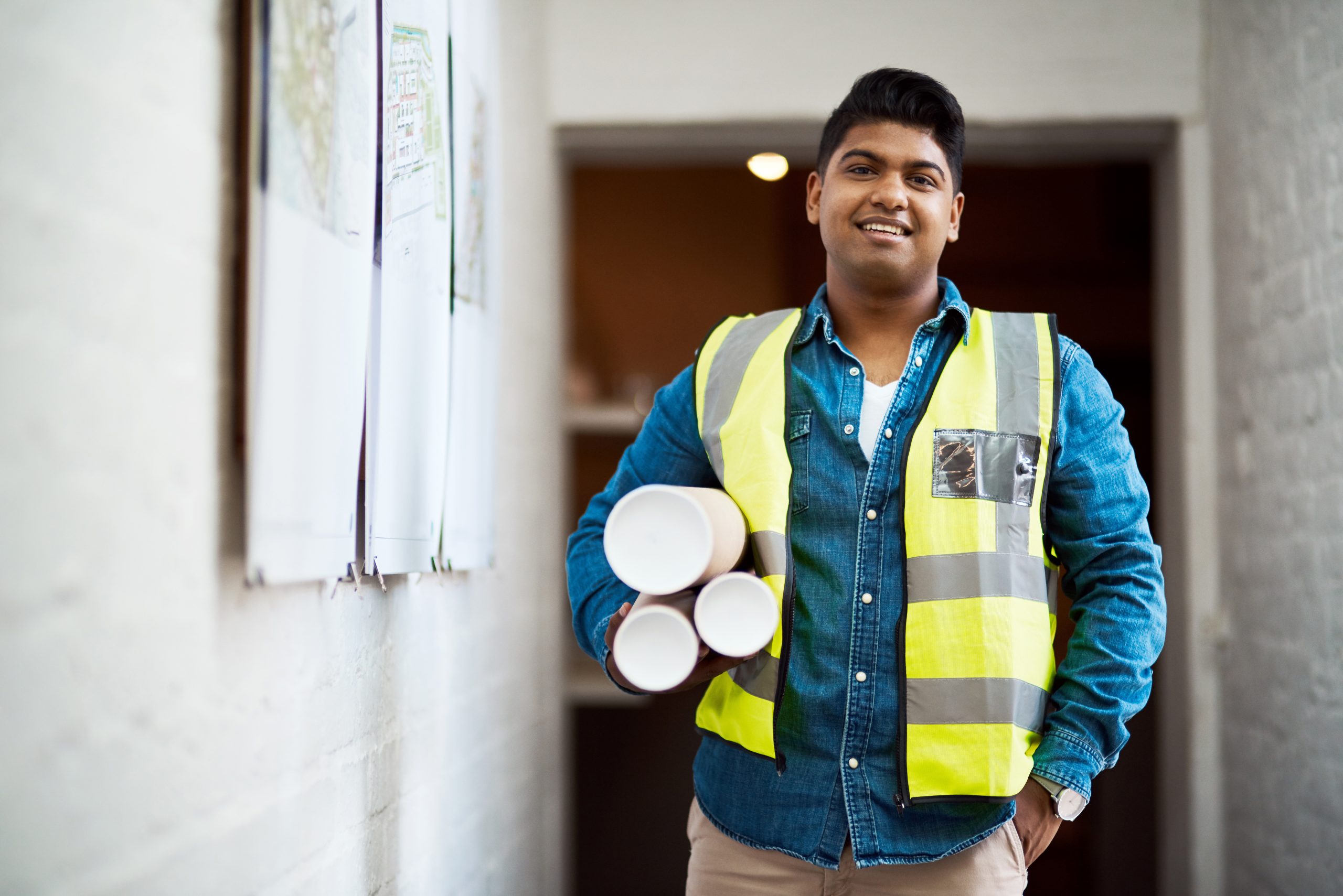 Shot of a young engineer holding blueprints on a construction site.