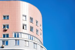 Modern multi-storey building against the blue sky. Sale of apartments in new building. Copy space.